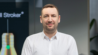 Gary Lawson, Global Sales Director for Well Completions Solutions, standing in front of a Welltec display with a professional smile.