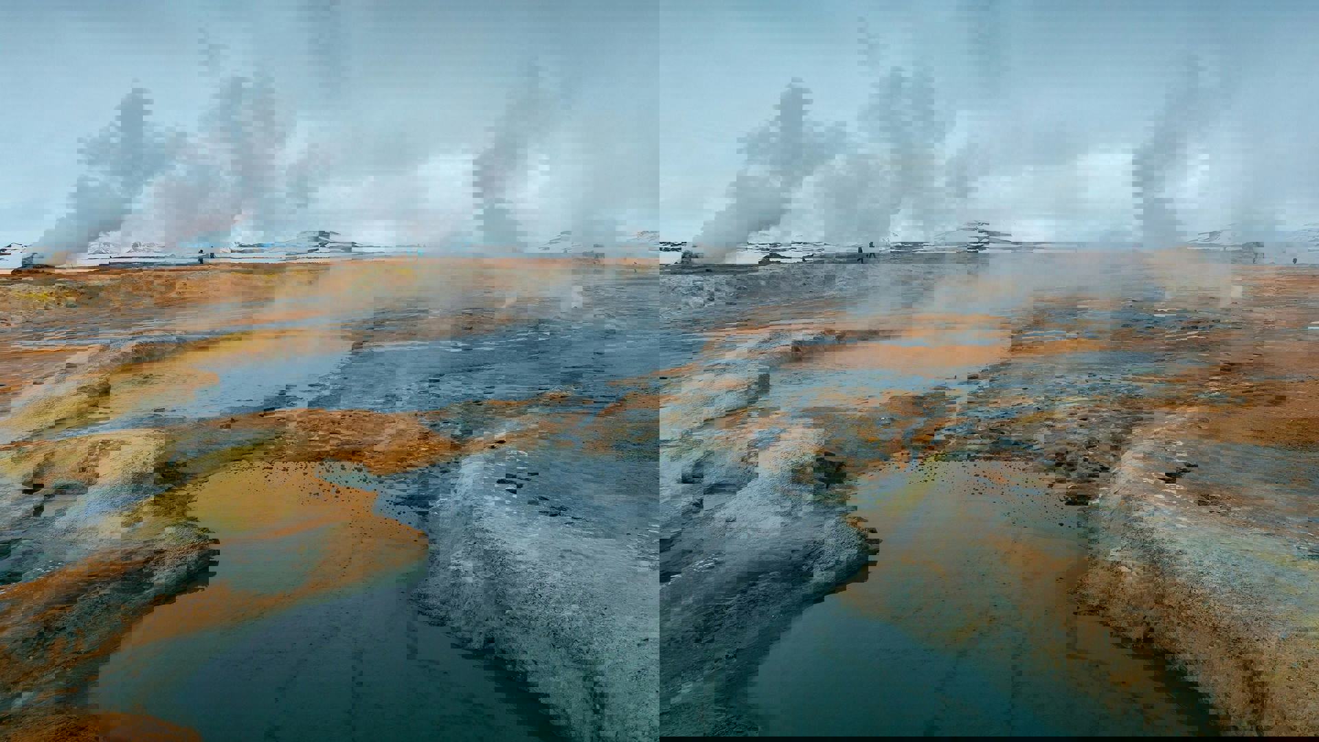 Geothermal landscape with visible steam vents indicating high and low temperature zones, representing conditions around geothermal wells.