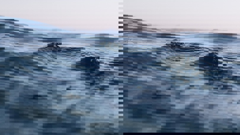 Close up of calm ocean surface with gentle waves at dusk, showcasing the texture and movement of the water.