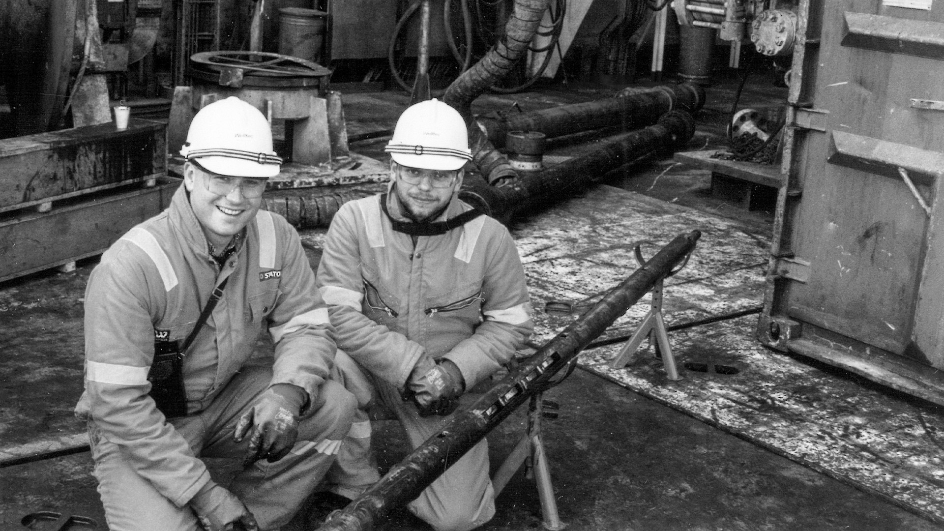 Two engineers in coveralls and hard hats pose on a rig site in 1987 with the original prototype of the Well Tractor developed by Jørgen Hallundbæk.