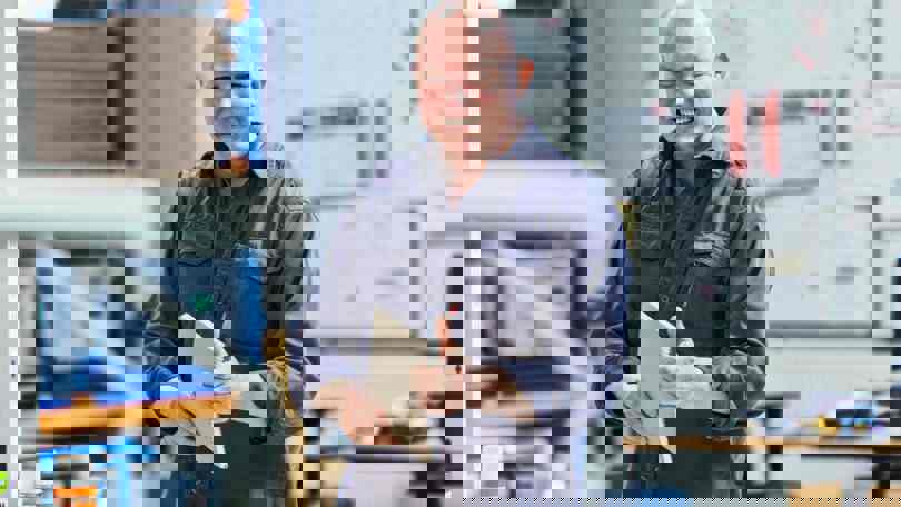 A Welltec employee smiling and holding a notebook inside a workshop or production facility, representing the company’s positive and professional work environment.