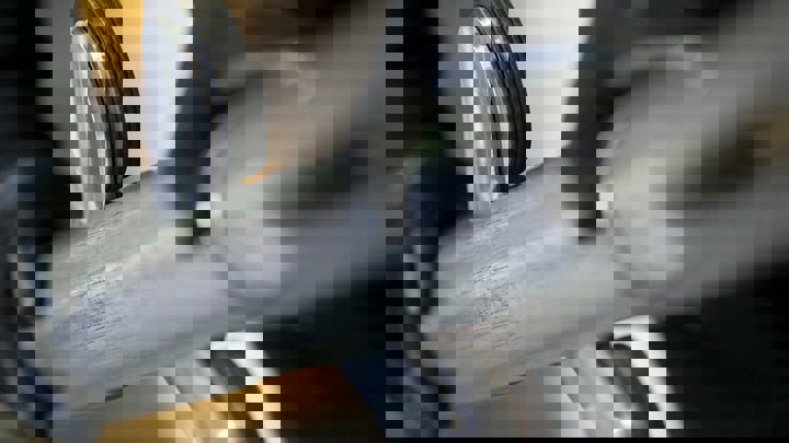 Close up of a gloved technician handling a well intervention tool with traction wheels designed for controlled movement inside the wellbore