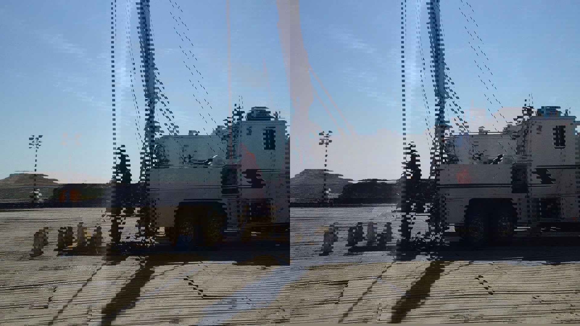 A construction worker maneuvers a crane, lifting heavy materials at a busy construction site.