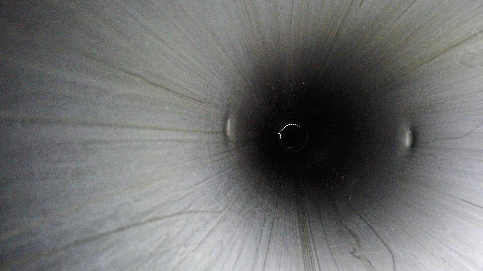 Interior view of a downhole safety valve showing the smooth surface and depth of the pipe, with a small opening at the end. 