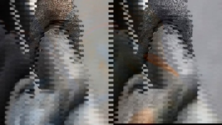 A close up of gloved hands gripping a pipe showing the surface texture and a small bolt attachment. 