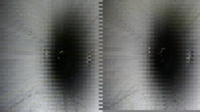 Interior view of a deep, cylindrical downhole safety valve (DHSV) tube showing smooth metallic walls and concentric alignment.