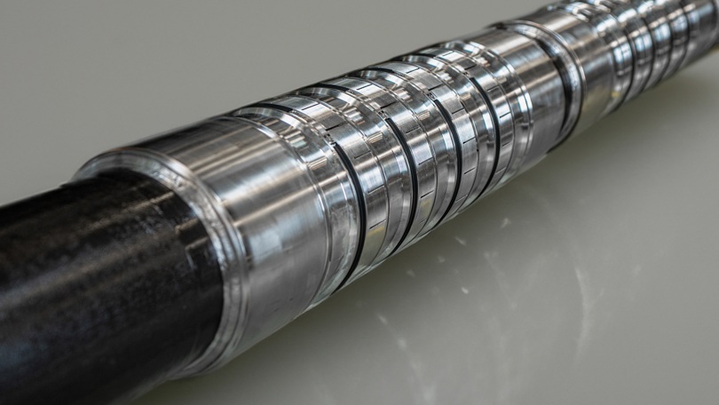 Close up of a Welltec completion tool showing slotted metal sections and precision engineered components for zonal isolation in a wellbore.