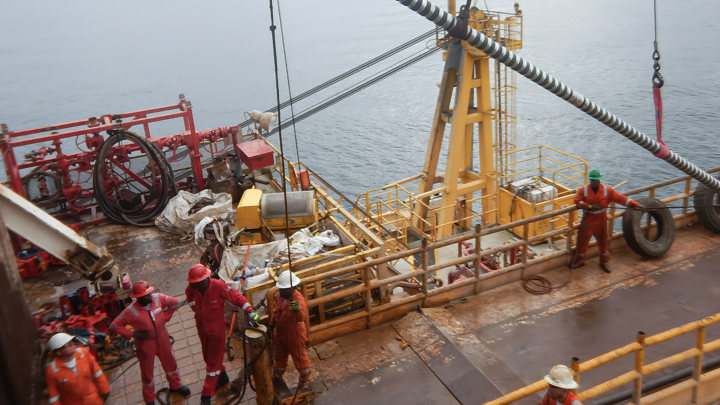 Offshore engineers on a platform handle equipment during cement replacement in an Albian reservoir off Albania's coast.