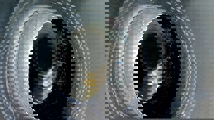 Close-up view inside a metallic tubular, showing the inner surface and concentric alignment of the internal components.